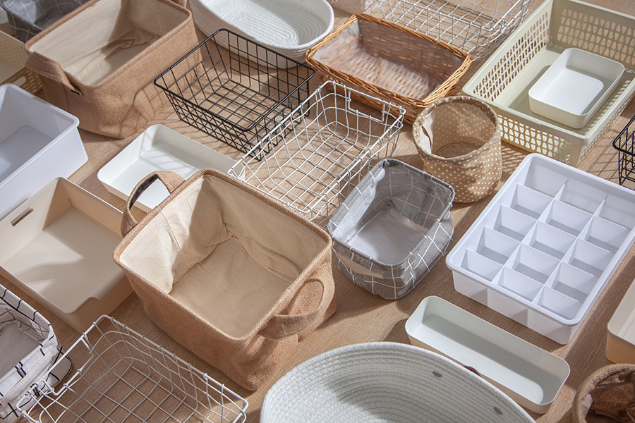 An image of Marie Kondo's storage boxes, containers, and baskets of various sizes and shapes, laid out flat. These items are used for tidying up wardrobes and represent the KonMari method of organization. This image showcases the concept of closet organizing with the help of specially designed organizing boxes.